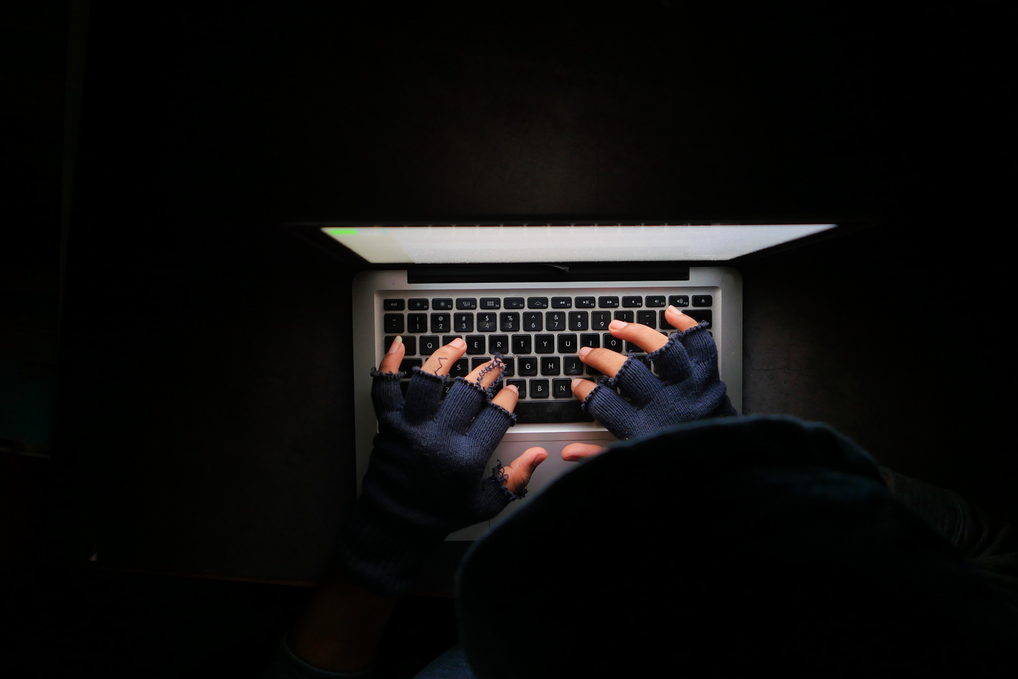 Hacker Hand Stealing Data from Laptop Top down